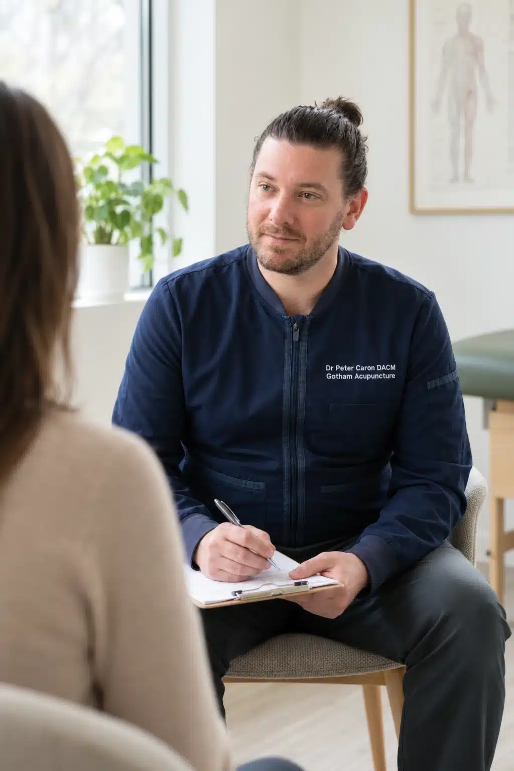 Dr. Peter Caron taking notes while a patient describes her symptoms